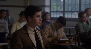 Movie still from “Indignation” (2016), directed by James Schamus – A young man sitting in front of a group of other people; Medium shot, Over the shoulder angle