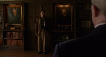 Movie still from “Indignation” (2016), directed by James Schamus – A man standing in front of a portrait of a man; Wide shot, Low angle