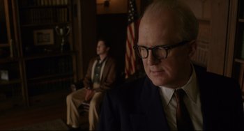 Movie still from “Indignation” (2016), directed by James Schamus – A man in a suit and tie sitting next to another man in a suit; Medium shot, Low angle