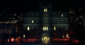 Movie still from “Inferno” (1980), directed by Dario Argento – A large building lit up at night with lights on it; Extreme Wide shot, Low angle