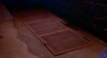 Movie still from “Inferno” (1980), directed by Dario Argento – An open wooden door in the middle of a room; Extreme Close Up shot, High angle