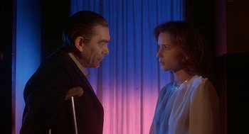 Movie still from “Inferno” (1980), directed by Dario Argento – A man and a woman standing next to each other in front of a curtain; Medium shot, Low angle