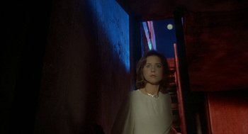 Movie still from “Inferno” (1980), directed by Dario Argento – A woman standing in a dark room with stairs; Medium shot, Low angle