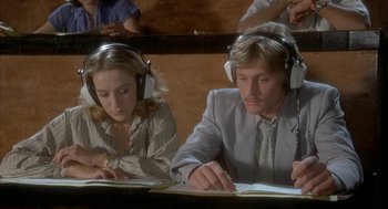 Movie still from “Inferno” (1980), directed by Dario Argento – A man and a woman wearing ear phones while sitting in front of a computer; Close Up shot, High angle