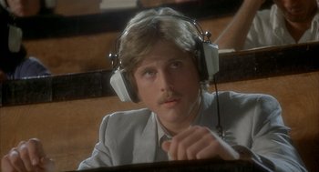 Movie still from “Inferno” (1980), directed by Dario Argento – A man with a mustache wearing headphones and a suit; Close Up shot, Low angle