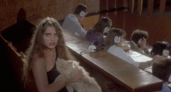 Movie still from “Inferno” (1980), directed by Dario Argento – A woman holding a cat in front of a group of people sitting at a bar; Medium shot, High angle