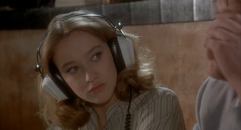Movie still from “Inferno” (1980), directed by Dario Argento – A woman wearing headphones while sitting in a room; Close Up shot, Over the shoulder angle