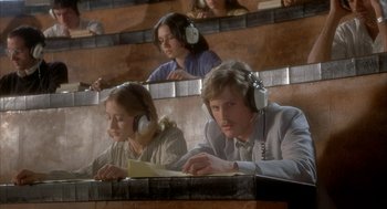 Movie still from “Inferno” (1980), directed by Dario Argento – A man and a woman wearing ear phones sit at a table; Medium shot, High angle