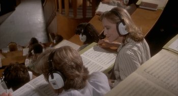 Movie still from “Inferno” (1980), directed by Dario Argento – A group of people sitting at a table wearing headphones; Medium shot, High angle