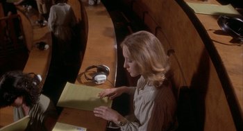 Movie still from “Inferno” (1980), directed by Dario Argento – A woman sitting at a table with papers in her hands; Medium shot, High angle