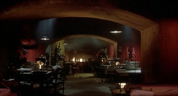 Movie still from “Inferno” (1980), directed by Dario Argento – A room filled with lots of furniture and a fire place; Wide shot, High angle