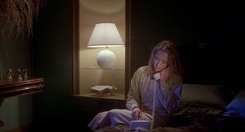 Movie still from “Inferno” (1980), directed by Dario Argento – A woman sitting on a bed talking on a phone; Medium shot, High angle