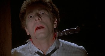 Movie still from “Inferno” (1980), directed by Dario Argento – A man with a knife in his mouth with blood all over his face; Close Up shot, Low angle