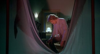 Movie still from “Inferno” (1980), directed by Dario Argento – A man in a white shirt is looking through a curtain; Wide shot, Low angle