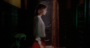 Movie still from “Inferno” (1980), directed by Dario Argento – A woman standing in front of an open door; Medium shot, Over the shoulder angle