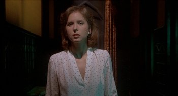 Movie still from “Inferno” (1980), directed by Dario Argento – A woman in a white polka dot shirt standing in front of a window; Close Up shot, Low angle
