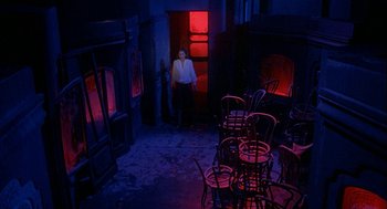 Movie still from “Inferno” (1980), directed by Dario Argento – A man standing in a room with a lot of chairs; Wide shot, High angle