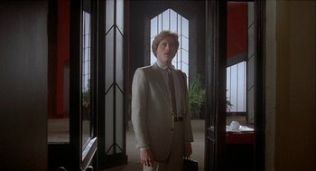 Movie still from “Inferno” (1980), directed by Dario Argento – A man in a suit standing in front of an open door; Medium shot, Low angle
