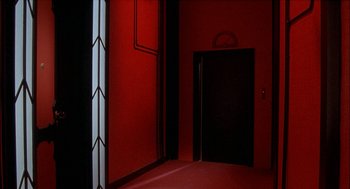 Movie still from “Inferno” (1980), directed by Dario Argento – A room with a red wall and a black door; Wide shot, High angle