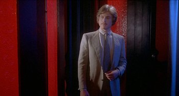 Movie still from “Inferno” (1980), directed by Dario Argento – A man wearing a suit and tie standing in front of a wall; Medium shot, Low angle