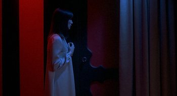 Movie still from “Inferno” (1980), directed by Dario Argento – A woman standing in front of an open door; Medium shot, Over the shoulder angle