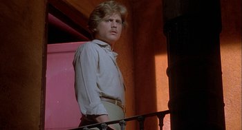 Movie still from “Inferno” (1980), directed by Dario Argento – A man standing next to a railing in front of a building; Medium shot, Low angle