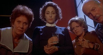 Movie still from “Inferno” (1980), directed by Dario Argento – A woman holding a glass of water between two other women; Medium shot, Low angle