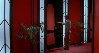 Movie still from “Inferno” (1980), directed by Dario Argento – A man standing in front of an open door in a room; Wide shot, High angle