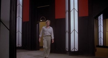 Movie still from “Inferno” (1980), directed by Dario Argento – A man in a white dress shirt and beige slacks walking in front of a building; Wide shot, Low angle