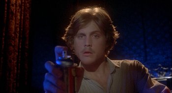 Movie still from “Inferno” (1980), directed by Dario Argento – A man holding a can of beer in front of him; Close Up shot, Low angle