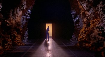 Movie still from “Inferno” (1980), directed by Dario Argento – A man standing in front of an open door at night; Extreme Wide shot, High angle