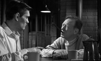 Movie still from “Inherit the Wind” (1960), directed by Stanley Kramer – Two men sitting at a table talking to each other; Medium shot, Over the shoulder angle