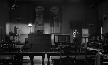 Movie still from “Inherit the Wind” (1960), directed by Stanley Kramer – A man standing in front of a desk in a room; Wide shot, High angle