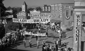 Movie still from “Inherit the Wind” (1960), directed by Stanley Kramer – A black - and - white photo of people marching down a street; Extreme Wide shot, High angle