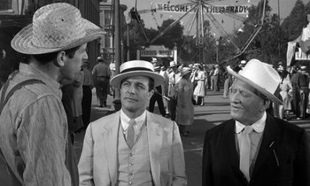 Movie still from “Inherit the Wind” (1960), directed by Stanley Kramer – A group of men standing next to each other on the street; Medium shot, Over the shoulder angle