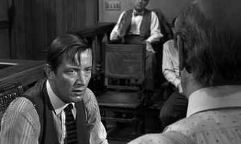 Movie still from “Inherit the Wind” (1960), directed by Stanley Kramer – A man in a suit and tie sitting on a chair; Medium shot, Over the shoulder angle