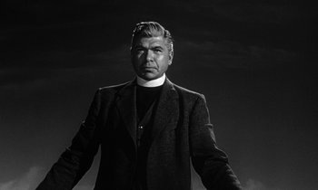 Movie still from “Inherit the Wind” (1960), directed by Stanley Kramer – A man wearing a priest's outfit standing in front of a dark sky; Medium shot, Low angle