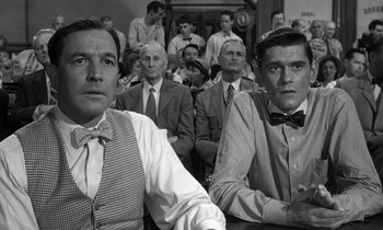 Movie still from “Inherit the Wind” (1960), directed by Stanley Kramer – A group of men sitting next to each other in front of a crowd; Medium shot, Over the shoulder angle