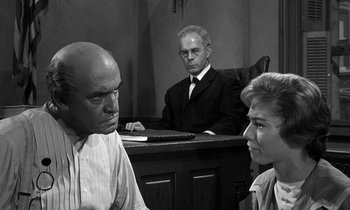 Movie still from “Inherit the Wind” (1960), directed by Stanley Kramer – A man and a woman in a courtroom with an older man; Medium shot, Over the shoulder angle
