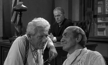 Movie still from “Inherit the Wind” (1960), directed by Stanley Kramer – A group of men sitting around a table talking to each other; Medium shot, Over the shoulder angle