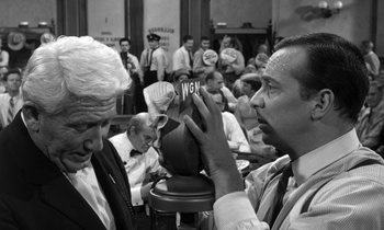 Movie still from “Inherit the Wind” (1960), directed by Stanley Kramer – Two men are sitting at a table and one of them is holding up a card; Close Up shot, Over the shoulder angle