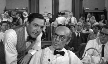 Movie still from “Inherit the Wind” (1960), directed by Stanley Kramer – Two men are posing for a picture in front of an audience; Medium shot, Over the shoulder angle