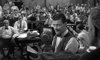 Movie still from “Inherit the Wind” (1960), directed by Stanley Kramer – An old photo of a man holding a microphone in front of an audience; Medium shot, Over the shoulder angle