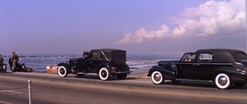 Movie still from “Inside Daisy Clover” (1965), directed by Robert Mulligan – A couple of old cars driving down a street; Wide shot, High angle