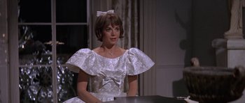 Movie still from “Inside Daisy Clover” (1965), directed by Robert Mulligan – A woman in a white dress sitting at a table; Medium shot, Over the shoulder angle