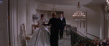 Movie still from “Inside Daisy Clover” (1965), directed by Robert Mulligan – A woman in a white dress standing next to a man in a black suit; Wide shot, Low angle