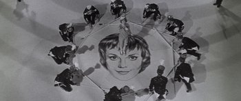 Movie still from “Inside Daisy Clover” (1965), directed by Robert Mulligan – An old photo of a woman's face surrounded by people; Wide shot, Overhead angle