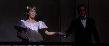 Movie still from “Inside Daisy Clover” (1965), directed by Robert Mulligan – A woman in a white dress is holding a fan; Medium shot, Low angle