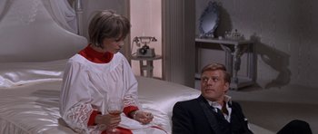 Movie still from “Inside Daisy Clover” (1965), directed by Robert Mulligan – A man and a woman sitting on a bed with a glass of wine; Medium shot, High angle
