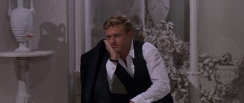 Movie still from “Inside Daisy Clover” (1965), directed by Robert Mulligan – A man in a white shirt and black vest holding a black jacket; Medium shot, Low angle